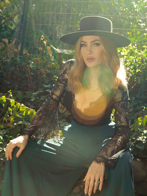 Sitting in her sunny garden, Micheline Pitt models the La Sorcière Top in Black from La Femme en Noir.