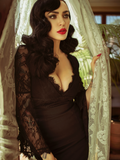 Micheline Pitt wearing the La Sorcière Top in Black while wrapped in white lace curtains.