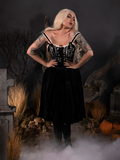 With her hands on her waist, Micheline Pitt models the Sleepy Hollow Gothic Tales Velour Skirt in Black by La Femme En Noir.