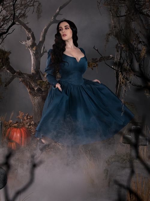 Rachel strolls through a foggy cemetery while modeling the  Sleepy Hollow The Lady Crane Dress in Vintage Blue from La Femme en Noir.