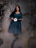 Full body image of Rachel Sedory holding the Sleepy Hollow Bird Carge Thaumatrope Wristlet.