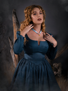 A closeup of Linda with her hands on her shoulders while modeling the Sleepy Hollow The Lady Crane Dress in Vintage Blue from La Femme En Noir.