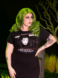Model wearing the BEETLEJUICE™ Lydia Dead Tee with one hand on her waist and looking off to the side.