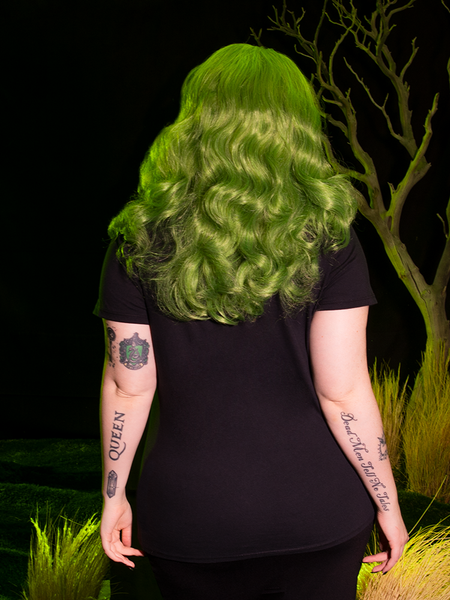 The back of the BEETLEJUICE™ Lydia Dead Tee as worn by female model with green hair.
