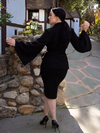 Back shot of Rachel posing with her arms up while wearing a black pencil skirt and the Metropolis Suit Jacket in Black.