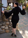 Rachel Sedory turned around and posing to show off the back of the Metropolis Suit Skirt in Black.