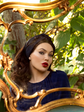 Gazing longingly into a gold-plated mirror, Micheline Pitt rocks a blue, flowy top with Art Deco Head Scarf in Navy Ponte. 