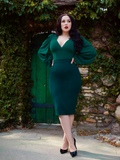 With her hands on her hips, Rachel looks off in the distance while wearing an all green, gothic retro inspired outfit from La Femme en Noir.