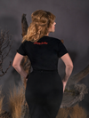 Standing in a foggy forest, Linda is turned away from the camera while modeling the Sleepy Hollow™ Protection Spell Tee.