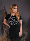 Linda, looking to the side with her hand on her hip, models the Sleepy Hollow™ Protection Spell Tee from alt clothing brand La Femme En Noir.