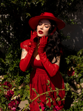 With her hands held up to her chin, Micheline Pitt soaks up the sun's rays while wearing an all crimson outfit including the Bolero Hat in Crimson.