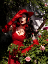 Micheline Pitt modeling the Bolero Hat in Crimson with matching elbow length vinyl gloves and dress.
