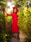 Ashley posing in a red rose garden wearing the Mourning Dress in Crimson Lace From La Femme en Noir.