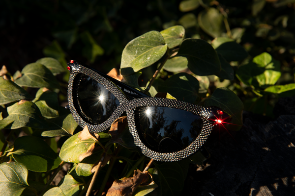 The red ruby of the snakes eye glistens on the Serpent Sunglasses in Black from La Femme en Noir. 