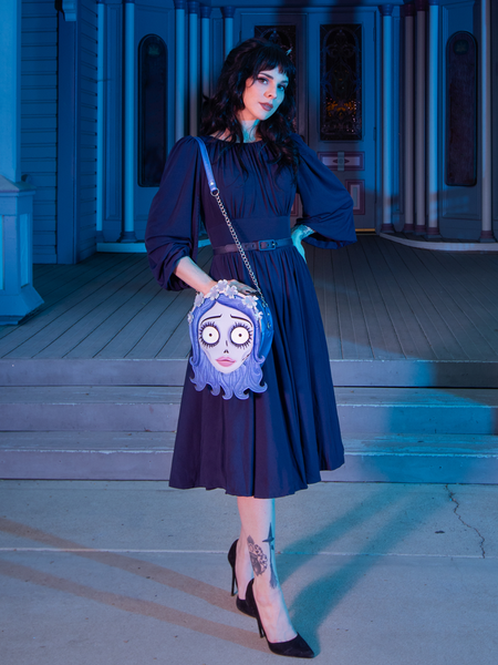 Model places one hand on her hip while modeling the Salem Dress in Navy and wearing the corpse bride Emily bag and modeling the Salem Dress in Navy.