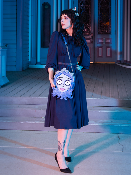 A full length shot of female model wearing the Salem Dress in Navy paired with the Emily Corpse Bride bag.