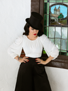 Micheline Pitt wearing the Salem Top in Ivory paired with black loose fitting pants and black tophat.