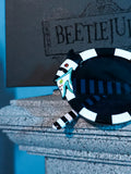 Close up of the frame on the BEETLEJUICE™ Sandworm Spectacles sat in front of the retail box.