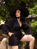 Micheline Pitt wearing an all black outfit including the Opera Black Crepe Satin Shorts from La Femme en Noir.
