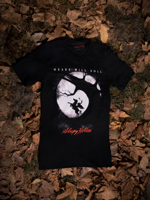 The Sleepy Hollow™ Heads Will Roll Tee laid out on a bed of dead leaves.