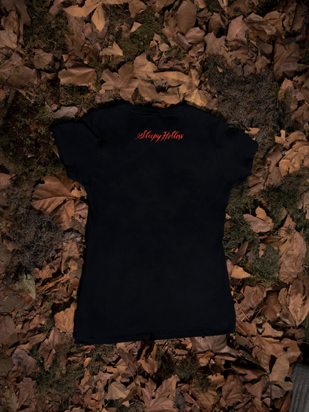 A closeup photo of the back of the Sleepy Hollow™ Protection Spell Tee on the floor with dead leaves.