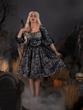 Standing in a foggy cemetery with her hand on her shoulder, Micheline wears the Sleepy Hollow™ Lady Van Tassel Guipire Lace Dress from La Femme En Noir.