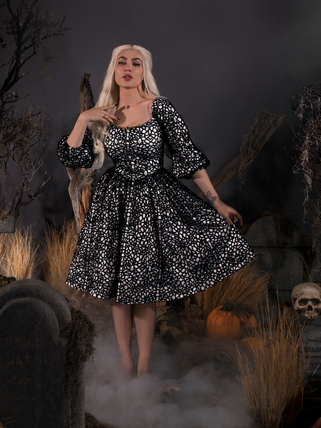 Standing in a foggy cemetery with her hand on her shoulder, Micheline wears the Sleepy Hollow™ Lady Van Tassel Guipire Lace Dress from La Femme En Noir.