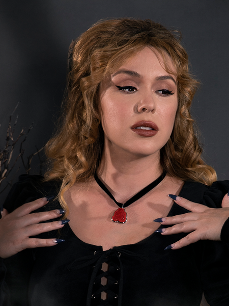 With her hands on her shoulders, Linda models the Sleepy Hollow™ Van Garrett Wax Seal Necklace by La Femme En Noir