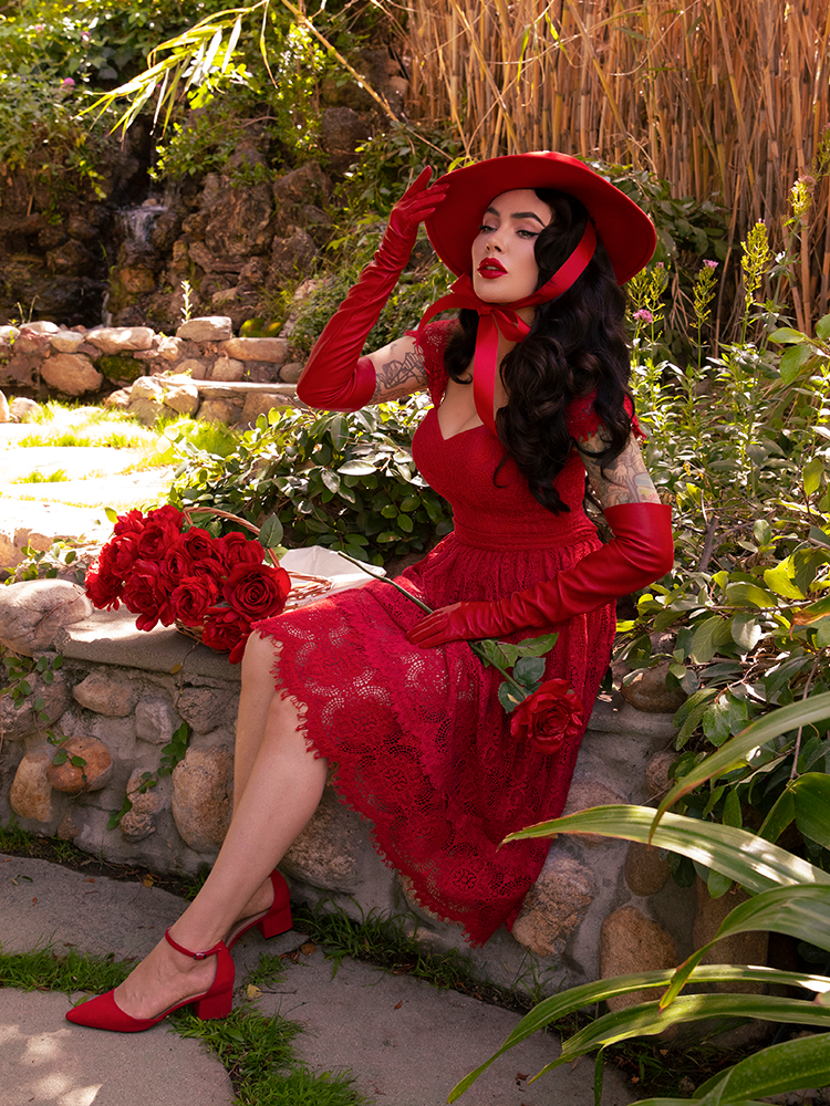 Profile shot of Micheline Pitt in a crimson colored gothic skirt with matching goth retro style top.