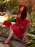 Micheline Pitt sitting on a stone wall in her Southern Gothic Skirt in Crimson.