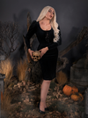 Full length shot of Micheline Pitt standing in the Sleepy Hollow Gothic Tales Velour Wiggle Dress in Black.