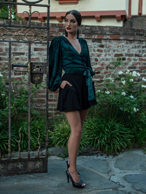 Full length shot of Aliza Schloesser posing next to a gothic style gate.