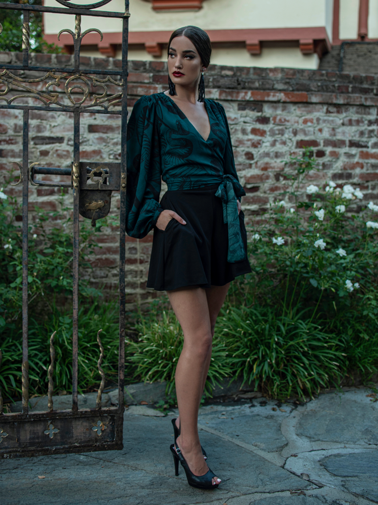 Full length shot of Aliza Schloesser posing next to a gothic style gate.