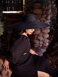 Hey face slightly obscured by her black sunhat, Ashley looks down while wearing the Thistle Two Piece Set in Black Chiffon from gothic glamour brand La Femme en Noir.