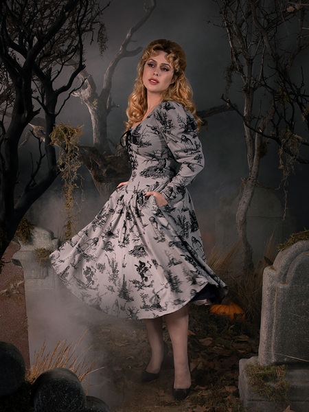 Linda standing in a fog drenched graveyard wearing a grey gothic style dress.