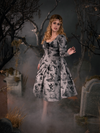 Linda eloquently posing in the Sleepy Hollow Gothic Tales Toile Swing Dress in Grey from gothic dress maker and retailer La Femme en Noir.