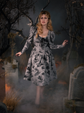 Linda playfully walking through a haunted cemetery while wearing the Sleepy Hollow Gothic Tales Toile Swing Dress in Grey.