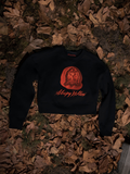 The Sleepy Hollow™ Van Garrett Wax Seal Cropped Sweatshirt laid over a bed of dead leaves.