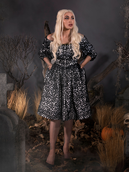 With her hands in her pockets, Micheline looks like a gothic vision in the Sleepy Hollow™ Lady Van Tassel Guipire Lace Dress by La Femme En Noir.