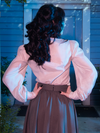 The back of The Edwardian Blouse With Cravat paired with grey flowing skirt. 