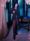Tim Burton's CORPSE BRIDE™ Victor Peplum Blazer in Spruce Green as worn by Stephanie a she stands in a dimly lit foyer in an old Victorian home. 