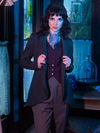 Closer image of Stephanie pulling out the lapels on her Tim Burton's CORPSE BRIDE™ Victor Peplum Blazer in Spruce Green as she stands in the foyer of her creepy old Victorian house.