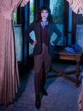 Stephanie stands in the foyer of her Victorian home while wearing the Tim Burton's CORPSE BRIDE™ Victor Pinstripe Pant in Dusty Olive from goth retro clothing company La Femme en Noir.
