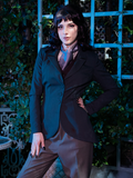 Stephanie poses in an outdoor haunted mansion setting, while wearing the Tim Burton's CORPSE BRIDE™ Victor Peplum Blazer in Spruce Green from goth clothing designer and retailer La Femme en Noir.