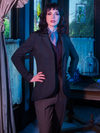 A close up shot of Stephanie wearing Tim Burton's CORPSE BRIDE™ Victor Peplum Blazer in Spruce Green while standing in a dimly lit Victorian style house.