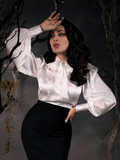 Looking in distress, Micheline Pitt shows off the Victorian Blouse in Ivory while standing in a foggy, haunted forest.