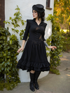 Model turns to look to the side while posing in the Victorian Dress in Black from goth style clothing brand La Femme en Noir.