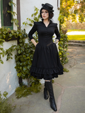 Raven haired goth model wearing the Victorian Dress in Black along with a pair of black boots and matching hat.