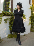 Model tucks her hands into the side pockets of the Victorian Dress in Black from goth clothing company La Femme en Noir.