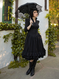 Giving a sly look, La Femme en Noir model holds an intricately stitched parasol to compliment her Victorian Dress in Black.
